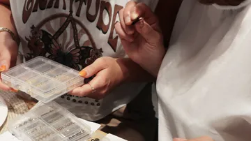 Two people sorting small beads at table.