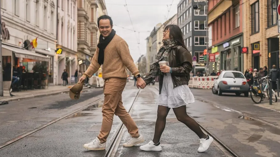 Couple holding hands, walking on city street.
