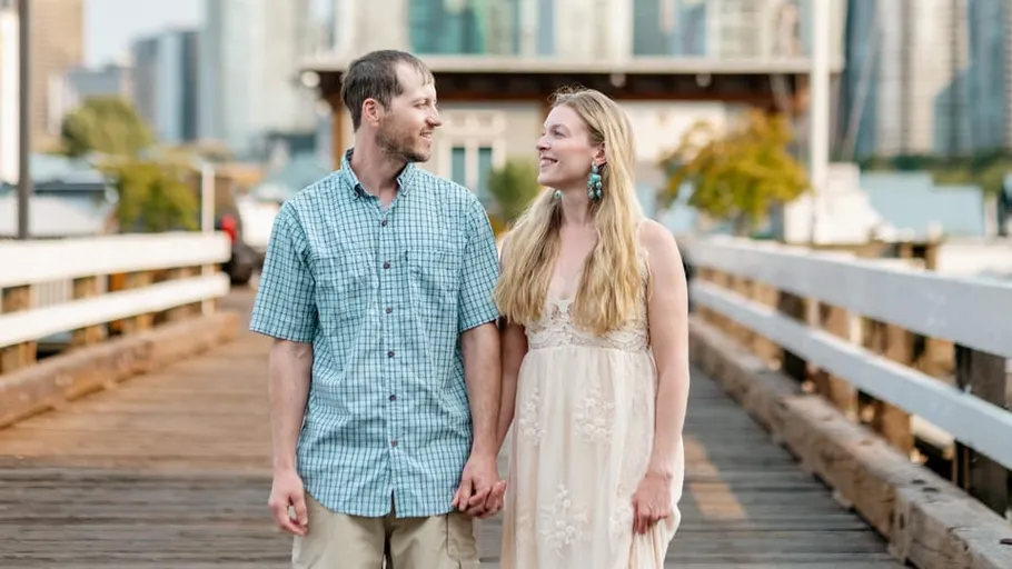 Couple holding hands on a wooden bridge.