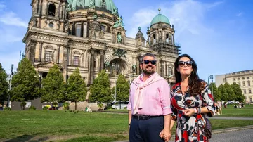 Couple walks in front of historic cathedral.