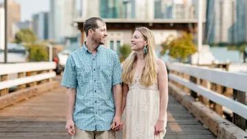 Couple walking on a city bridge smiling.