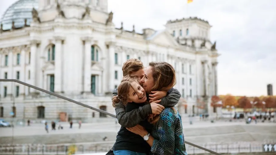 Family hugging in front of historic building.
