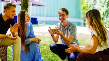 Gruppe genießt Kuchen im Freien auf Rasenfläche.