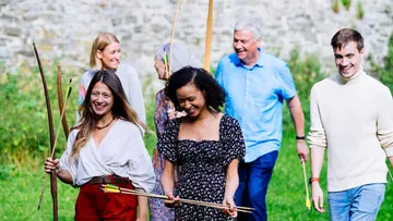 Group holding arrows walking on grass outdoors.
