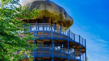 Observation tower with mushroom-like roof, under blue sky.