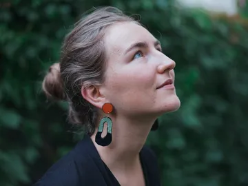 Woman with big earrings looking up, natural background.