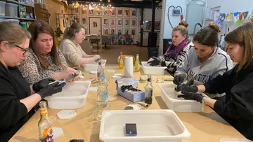 Women crafting at a large workshop table.