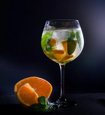 Cocktail mit Orangenscheiben und Minze im Glas.