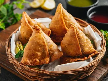Basket of fried samosas served with dips