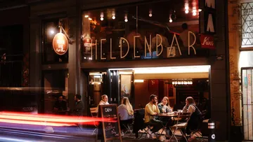 Leute sitzen abends draußen an einer Bar.