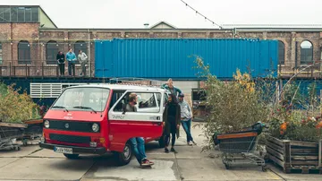 Red van with people outside urban building.