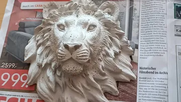 Lion sculpture on printed newspaper with text.