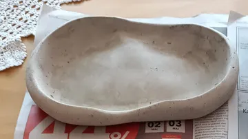 Betonschale auf Zeitungen auf Tisch.