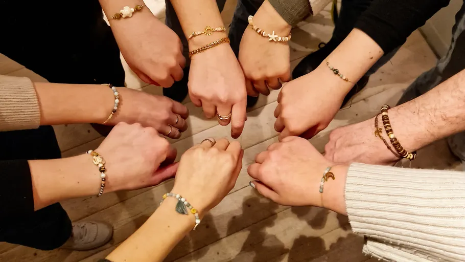 Hände im Kreis, tragen verschiedene Armbänder.