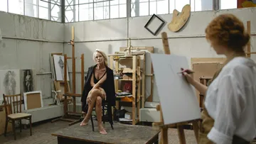 Künstler skizziert sitzendes Modell im Atelier.