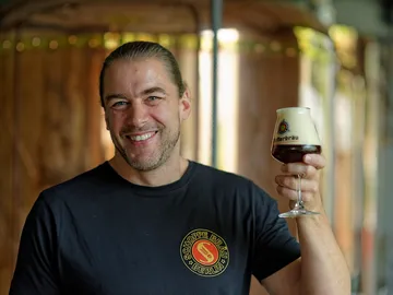 Mann hebt ein Glas Bier in einer Brauerei.