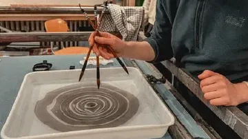 Person creating patterns with brushes in water.