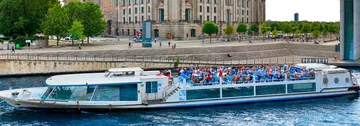 Boot fährt auf Fluss nahe historischem Gebäude.