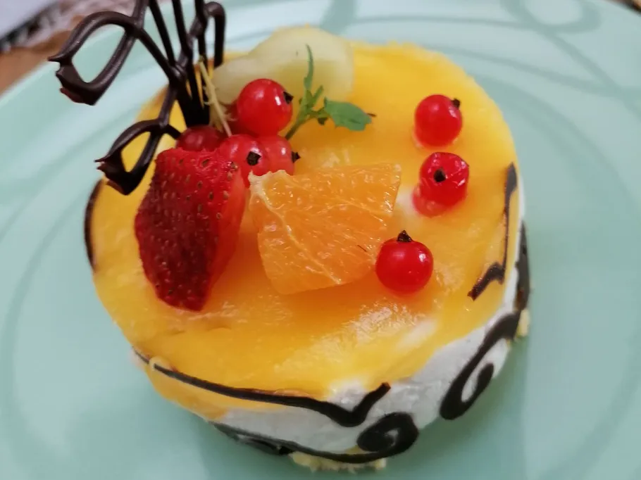 Fruit-topped cake with chocolate decoration.