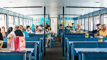 People seated inside a ferry, chatting casually.