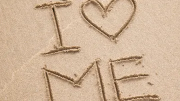 "I love me" written on sandy beach.