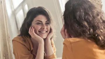Woman smiling at herself in mirror.
