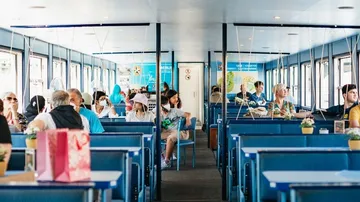 People sitting inside a ferry with blue seats.
