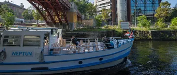 Boot namens Neptun segelt unter Brücke.