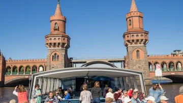 Boat tour passing under historic bridge towers.