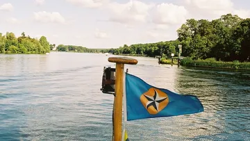Blue flag with star, river and trees.