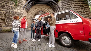 Group talking beside red van near gate.