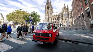 Red van near cathedral, people crossing street.