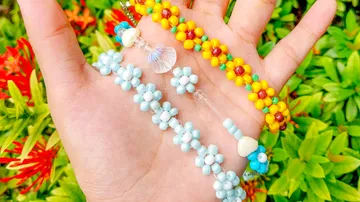 Hand hält bunte Perlenarmbänder im Freien.