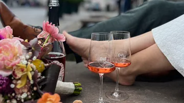 Two wine glasses beside bouquet and feet relaxing.