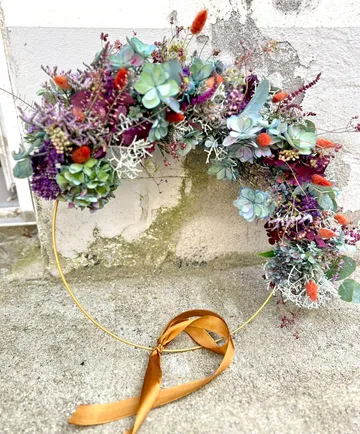 Floral wreath with ribbon on textured wall.