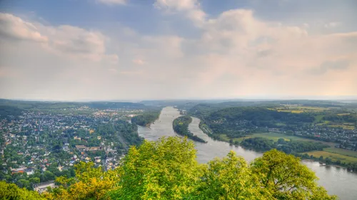 Fluss schlängelt sich durch üppiges Tal, bewölkter Himmel.