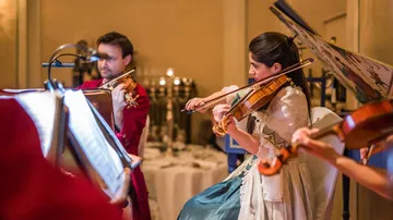 Musicians playing violins at elegant indoor event.