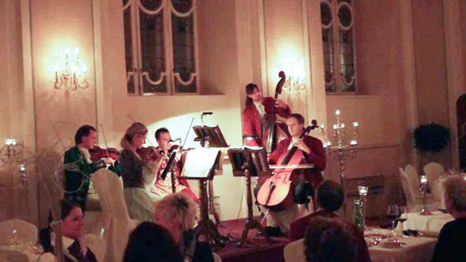Musicians perform on stage in elegant dining setting.