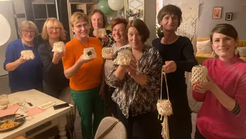 Group of women holding handcrafted items indoors.