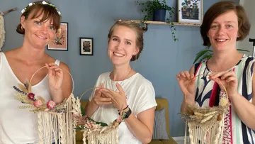 Three women holding decorative macramé rings indoors.