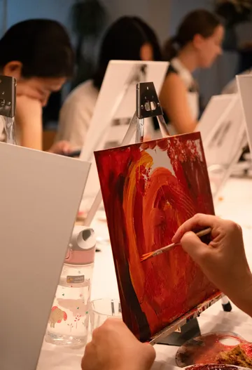 People painting on canvases at a workshop.