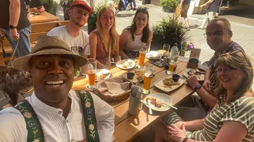 Group of people smiling, sitting at outdoor table.