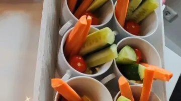 Mugs filled with carrot, cucumber, tomatoes.