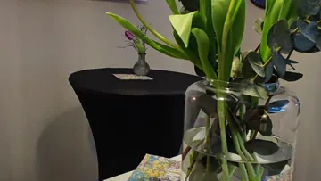 Glasvase mit Blumen auf Tisch drinnen.