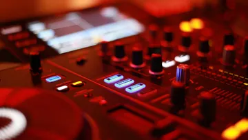 Close-up of a DJ mixer in red light.