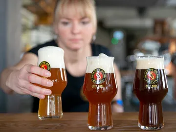 Glasses of beer are served by a woman.