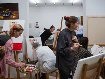 Artists paint various paintings in a studio.