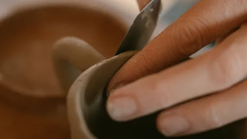 Hand formt Keramik mit einem Werkzeug.
