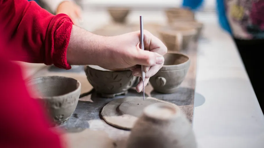 Hand carving clay pottery on a table.