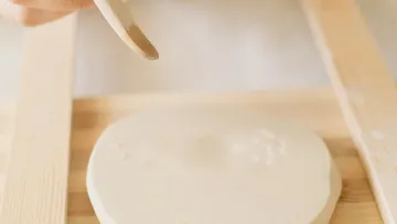 Hand smoothing pottery with wooden tool.